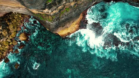 El-Dron-De-4k-Asciende-De-Las-Olas-Que-Se-Estrellan-Contra-Un-Acantilado-Alto-En-Bali,-Indonesia