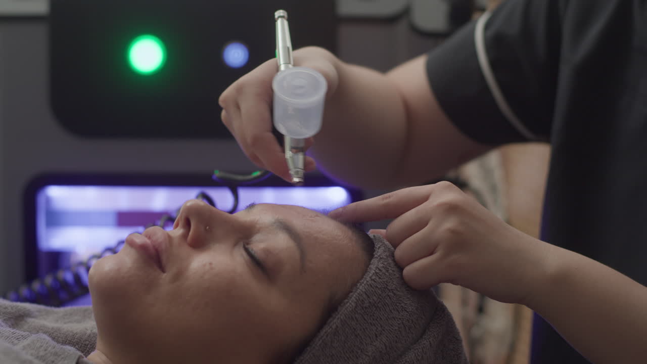 Beautician Moisturizing Facial Skin of Woman with Spraying Machine