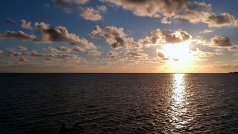 silhouette of person kayaking in the ocean during sunset, aerial forward shot