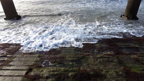 Foamy-Waves-Splashing-In-Between-Two-Stone-Pillars-In-Lisbon,-Portugal---high-angle-shot