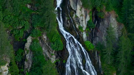 telefoto aérea de una estrecha cascada que desciende de la montaña, los alpes italianos