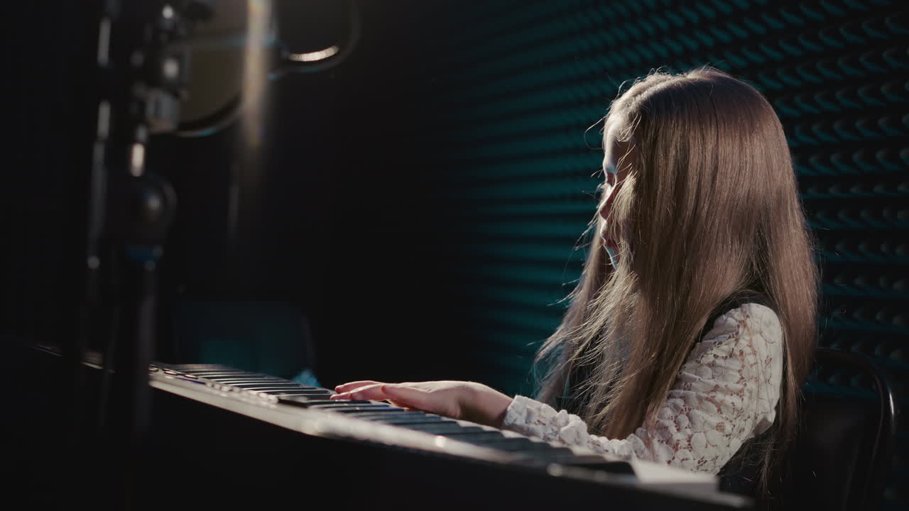 actuación musical de un niño en el piano en el estudio. una pequeña pianista crea una hermosa melodía en un instrumento digital en el estudio de grabación. actuación musical