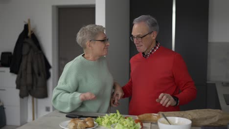 Pareja-Madura-Bailando-Mientras-Cocinan-Juntos-En-Casa---Gente-Madura-Divirtiéndose-Preparando-El-Almuerzo