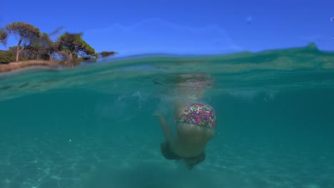 Escena-Semisubmarina-De-Una-Niña-Pequeña-Con-Máscara-De-Buceo-Saltando-En-El-Agua-De-Mar-De-La-Playa-De-Palombaggia-En-La-Isla-De-Córcega