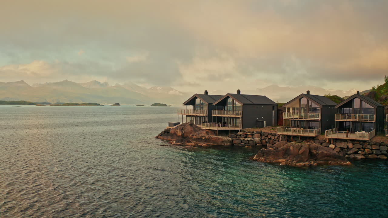 Aerial drone shot around the resort Hamn in Senja in the Lofoten Islands, Norway. View of the private suites located at the sea and the majestic landscape.
