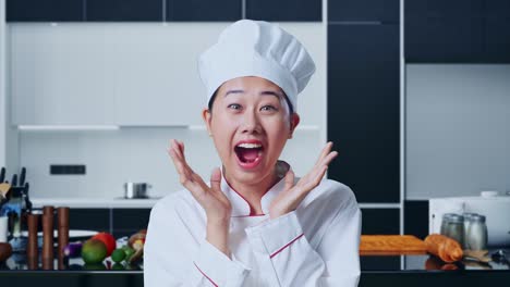 아시안 여성 요리사가 미소 짓고 가정 주방에서 와우라고 말하는 클로즈업