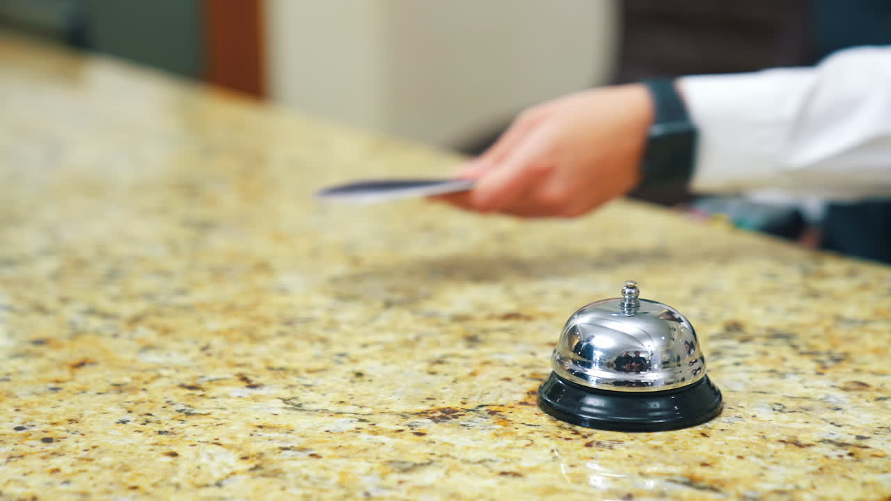 Guest makes card payment at check-in. Bell at hotel reception. Man in hotel lobby pay with nfc chip card. Blurred video of payment with terminal during checking in.