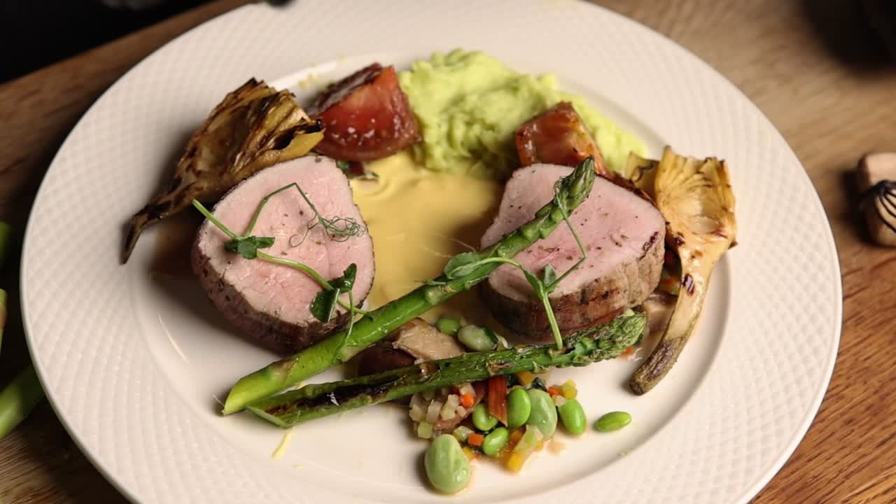 Chef's Hand Garnishing a Gourmet Plated Meal with Asparagus