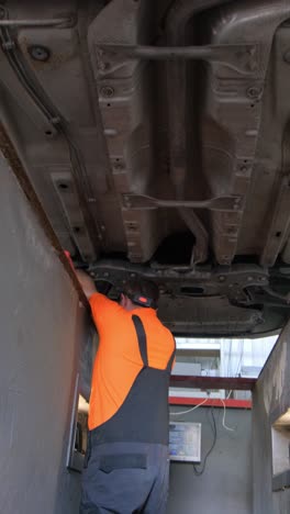 mechanic working under a car on a lift in an auto service garage