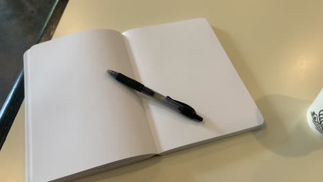 close up shot of a book with empty pages and a pen resting on top