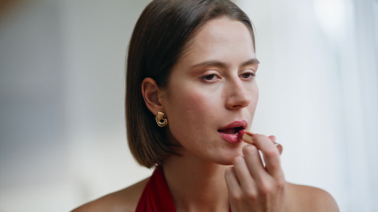 개인적인 손질 루틴으로 집에서 립스틱을 바르는 여성의 클로즈업 사진