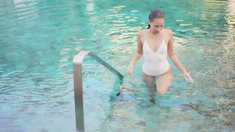 beautiful asian woman in white swimwear comes out of pool