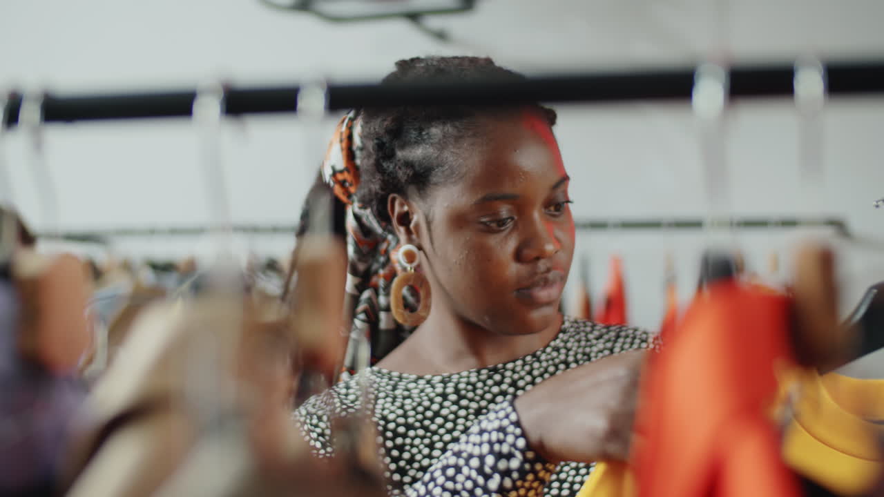 Mulher afro-americana escolhendo roupa nova em loja de roupas