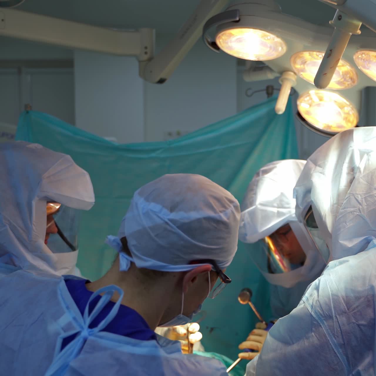 Group of doctors in operating theater. Teamwork of surgeons performing an operation to a patient in medical room in hospital.