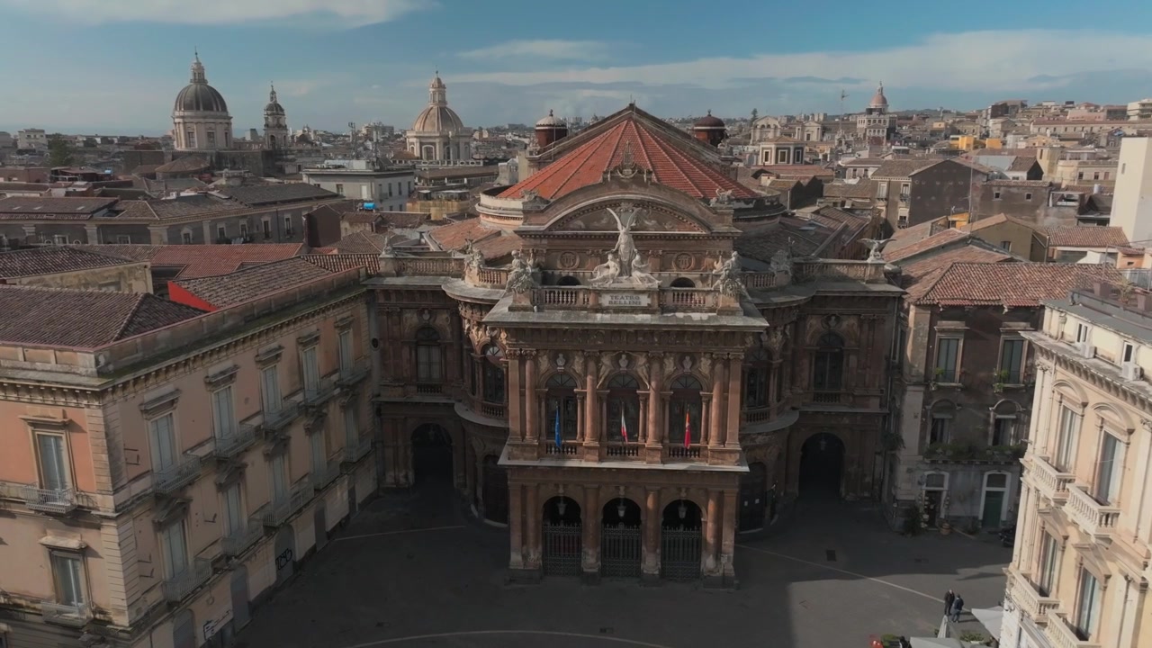 Storico Teatro Massimo Bellini con statue e colonne in una piazza mediterranea sotto un cielo parzialmente nuvoloso a Catania, Italia, ripreso dall'alto