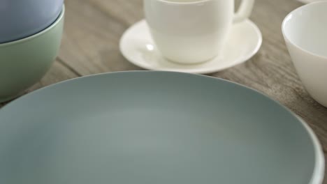 stacked stacks of porcelain and ceramic plates in pastel colors on a wooden textured kitchen table