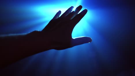 hand reaching out to cover shinning spot light