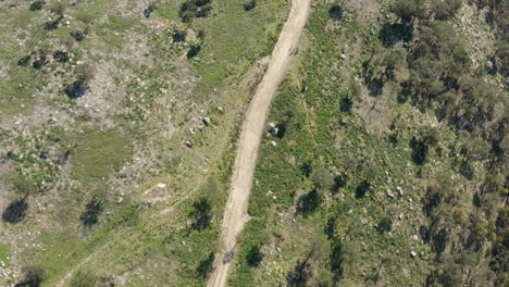 dirt path winding through hill in portuguese northern minho mountains - aerial birds eye view shot