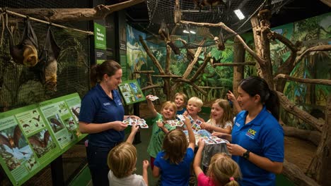 a fun educational experience with children at a zoo exhibit, learning about bats and their habitats with engaging activities and informative displays