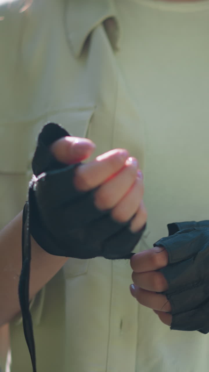 primer plano de individuos al aire libre quitando el guante de motociclista en la mano derecha con movimiento suave, el fondo presenta una vegetación exuberante borrosa