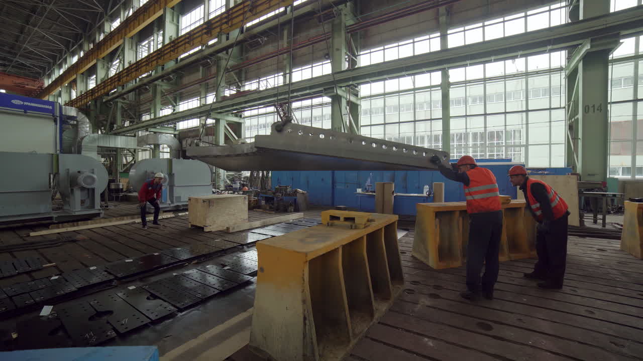 trabajadores industriales que manejan grandes componentes metálicos