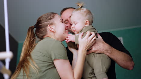 father holds a cute little baby in hands. mother entertains the child and kid is smiling adorably. low angle view.