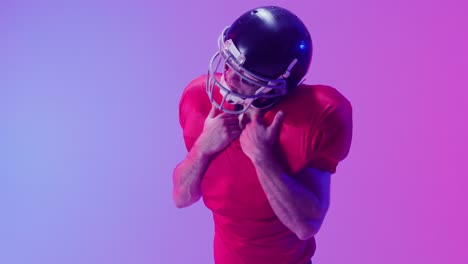 Video-of-caucasian-american-football-player-in-helmet-over-neon-purple-background