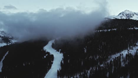 Panorama-Aéreo-De-Una-Pista-De-Esquí-En-Una-Montaña-Nevada-Alpina-Nublada-Por-La-Noche