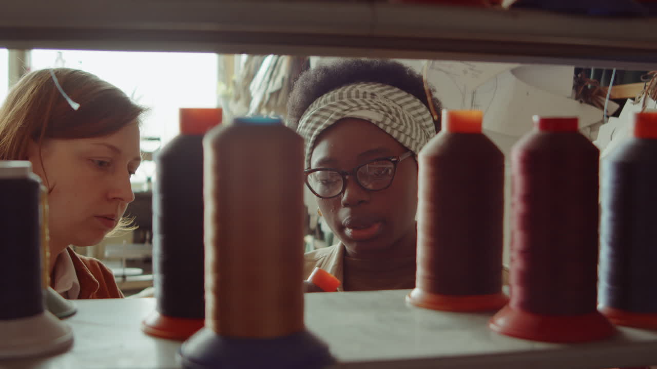 dos mujeres discutiendo bobinas de hilo en un taller