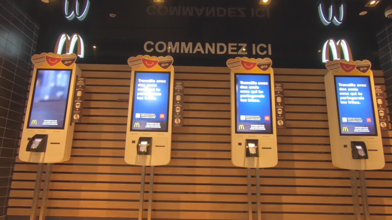 Editorial, four automatic order machines at McDonald's fast food restaurant. self ordering machines , to order meal and hamburgers. Digital touch screens and McDonalds logo on the wall.