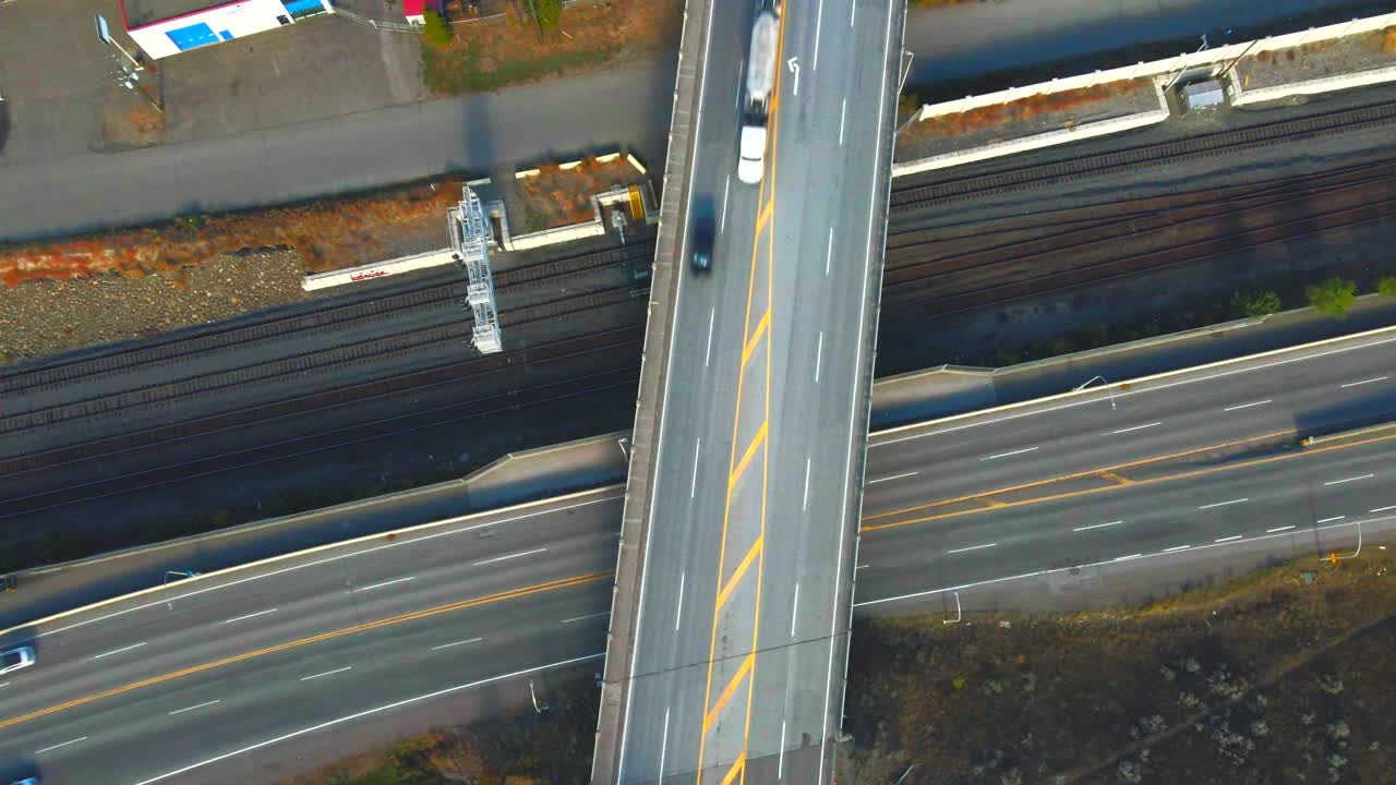 캐나다 bc주 캠루프스의 고속도로 1호를 가로지르는 옐로우헤드 고속도로 교량의 조감도 줌 아웃 드론 샷과 기차 선로가 배경에 있고 자동차와 세미트럭이 정상 속도로 이동합니다.