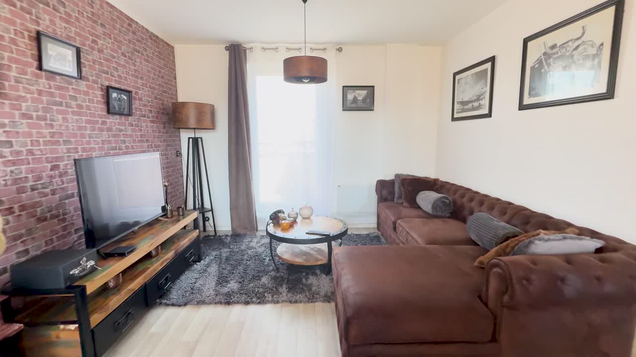 A smooth camera movement transitions from a retro lounge area with brown sofas and brick walls to a blue pool table under pendant lights, in bright natural lighting