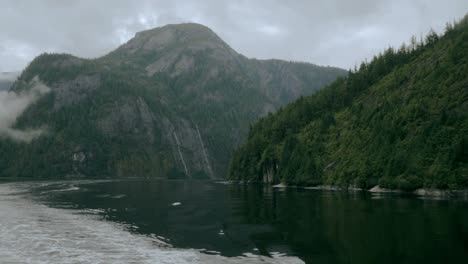 a depth shot of misty alaskan mountains as they sit on the water in a fjord