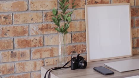 wooden frame with copy space on white background with plant on desk against brick wall