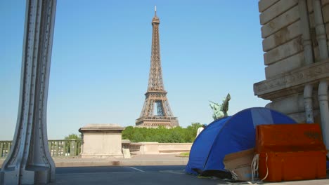 homeless family living in a tent under upper level of bir-hakeim bridge in paris, france with iconic eiffel tower in background. slider right