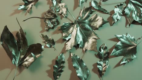 video of halloween autumn metallic leaves with copy space on green background