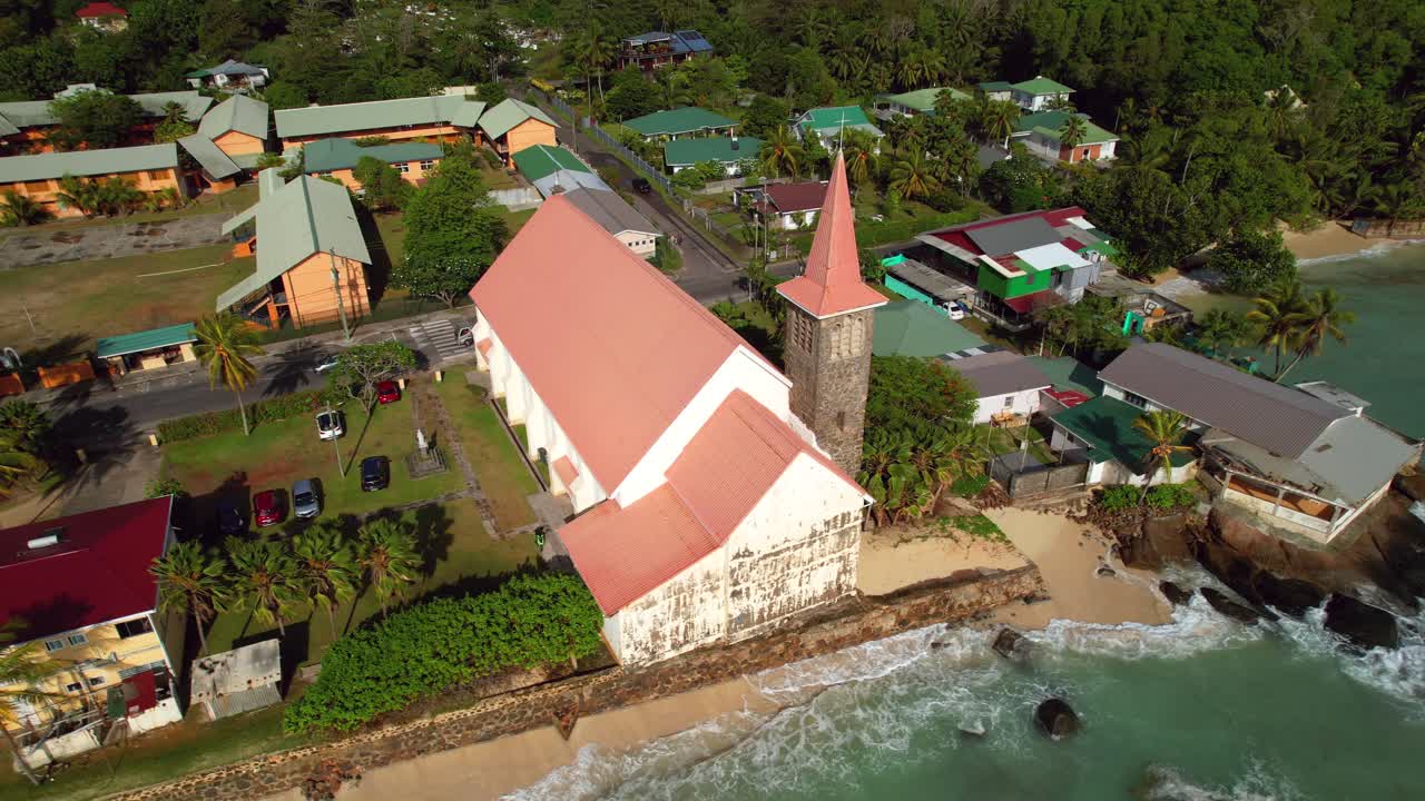 drones girando imágenes de la iglesia de san josé cerca de la costa, escuela pública y área residencial de anse royale beach, mahe, seychelles 30fps