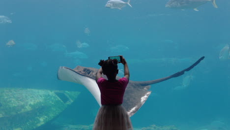 Kleines-Mädchen-Fotografiert-Fische-Im-Aquarium-Mit-Dem-Smartphone,-Fotografiert-Meerestiere,-Die-Im-Becken-Schwimmen,-Lernt-Etwas-über-Das-Leben-Im-Meer-Im-Wasserlebensraum-Und-Hat-Spaß-Im-Ozeanarium