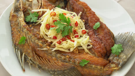 lubina frita con salsa de pescado y ensalada picante en el plato