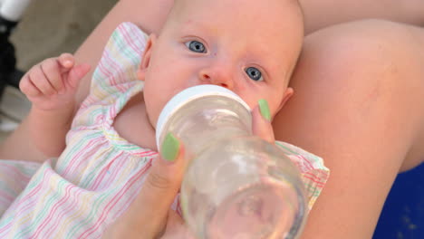 mother giving baby daughter to drink water from the bottle