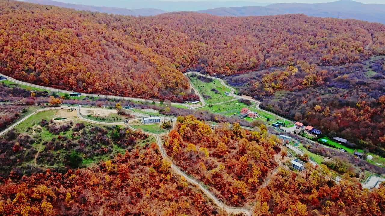 Aerial establishing view of Bear Sanctuary nestled, vibrant autumn Kosovo hills