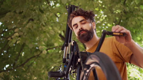 man adjusting bicycle pedals in yard