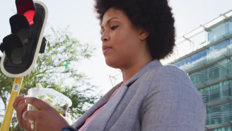 mujer biracial de talla plus comiendo ensalada en la ciudad