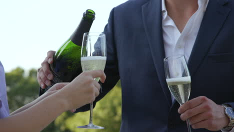 una pareja joven celebra sirviendo una botella de champán en cámara lenta