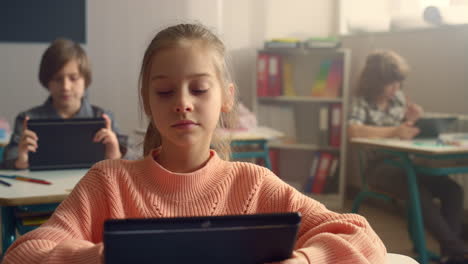 student browsing internet online on digital tablet during lesson at school