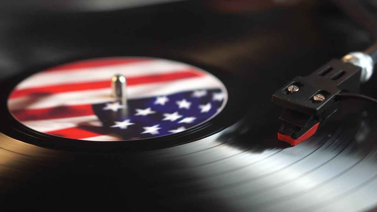 Long Play Vinyl Record With American Flag Spinning Under Needle of Turntable, Close Up