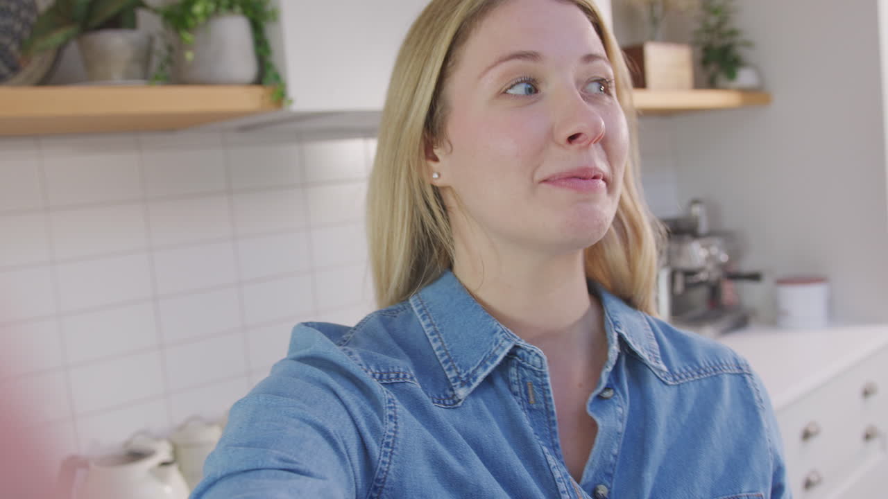 Point of view shot of woman vlogging making social media video as she carries camera around in kitchen at home - shot in slow motion