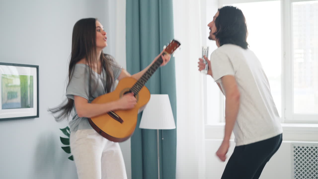 Couple Having Fun Playing Guitar and Dancing in Bedroom
