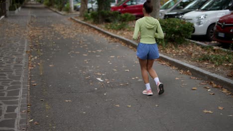 mujer corriendo por la calle de la ciudad en otoño