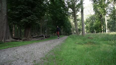 man riding a one-wheel board through a peaceful forest path on a sunny day